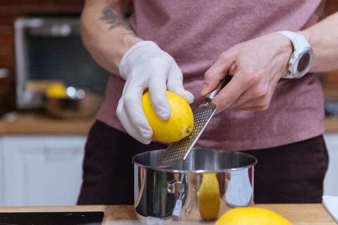 Zitrone gerieben auf einer Hand Reibe. Fotos - Anton Belitskiy